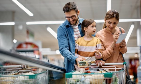 Happy parents with daughter going through checklist while buying in supermarket.